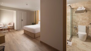 Hotelkamer met een bed, bureau, stoel, garderobe en badkamer met douche en toilet.
