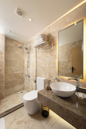 Un baño moderno con cabina de ducha, inodoro, lavabo y un espejo grande.