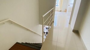 A staircase leading to an upper floor with a metal railing, a wooden floor, and a view of an adjacent room with a window. - Refined 3BR Duplex with Ocean Charm (Lima)