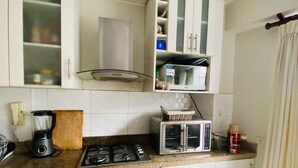 A kitchen with a gas stove, a microwave, a blender, and a toaster. - Refined 3BR Duplex with Ocean Charm (Lima)