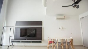 A modern living room with a flat-screen TV, a fireplace, a dining table with chairs, and a ceiling fan. - I Soho at I City by My Trip & My Stay (Shah Alam)