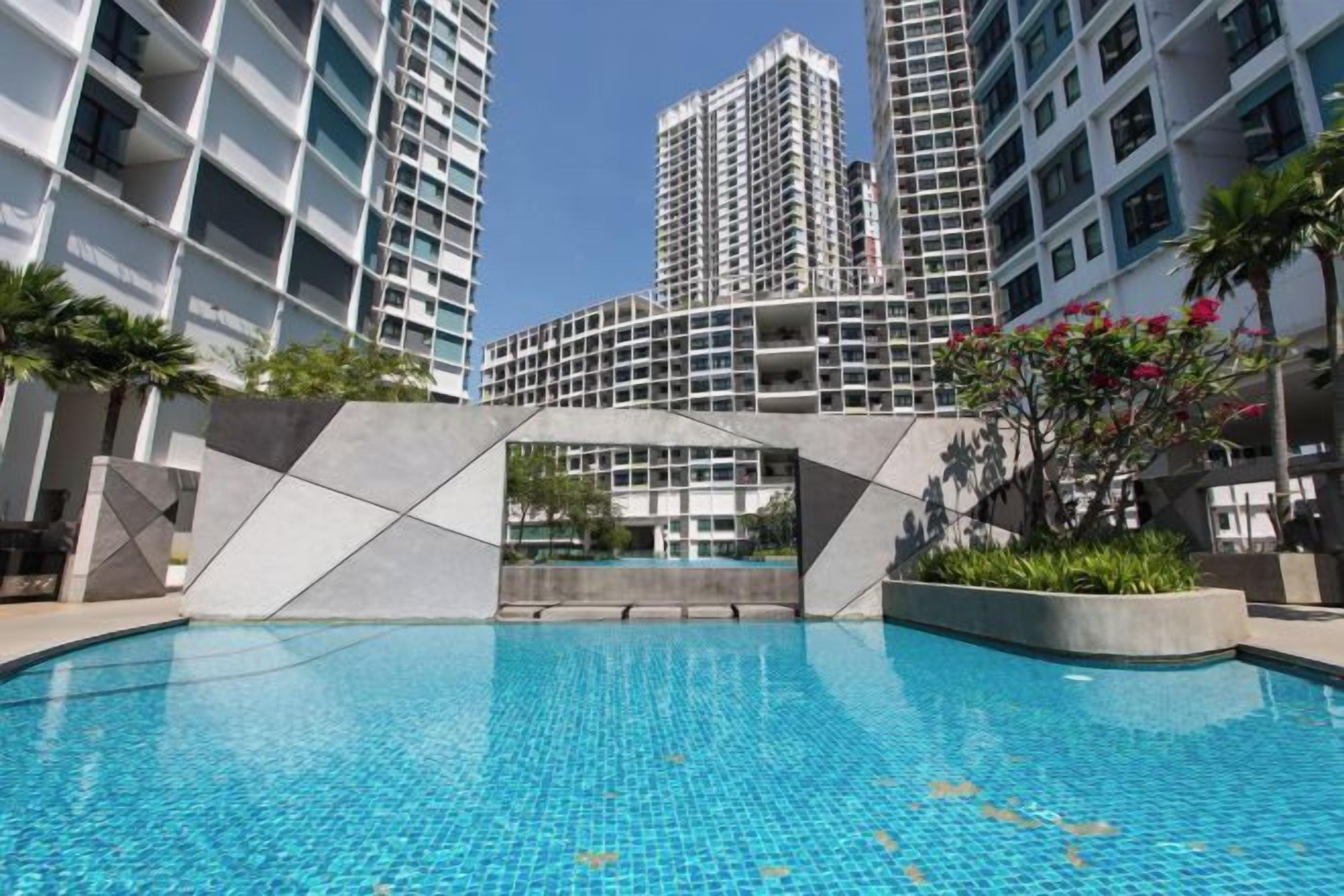 A swimming pool with a geometric bridge, surrounded by high-rise buildings.