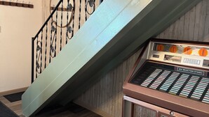 Een trap met een metalen leuning, een houten wand en een vintage stereo-installatie.