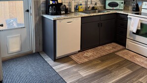 Een moderne keuken met een koffiebar bord, een vaatwasser, een magnetron en een fornuis.