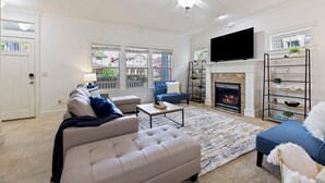 Un salon moderne avec une cheminée, un téléviseur et un ventilateur de plafond.