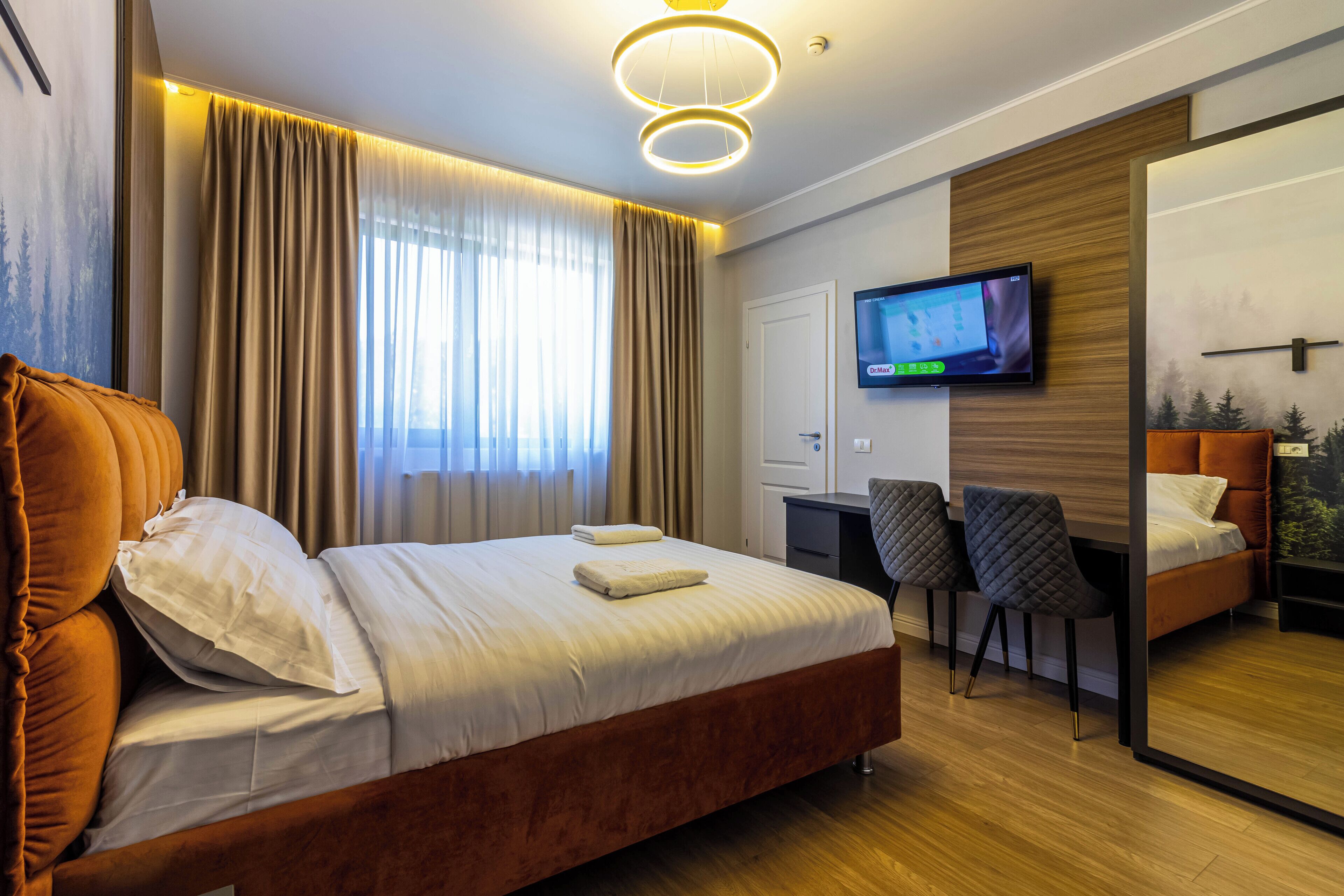 Una habitación de hotel moderna con una cama grande, un escritorio y un televisor.