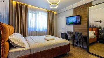 Una habitación de hotel moderna con una cama grande, un escritorio y un televisor.