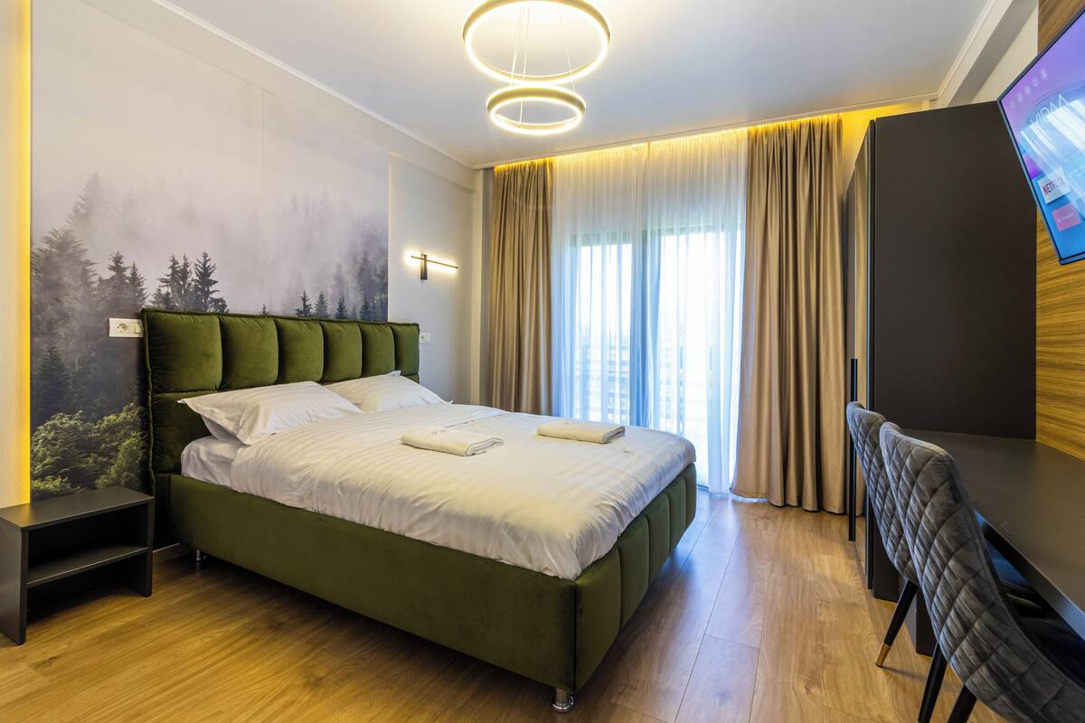 A modern hotel room with a large bed, a desk, and a TV.