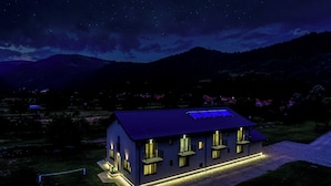 Una casa moderna con techo plano, múltiples ventanas y un exterior bien iluminado.