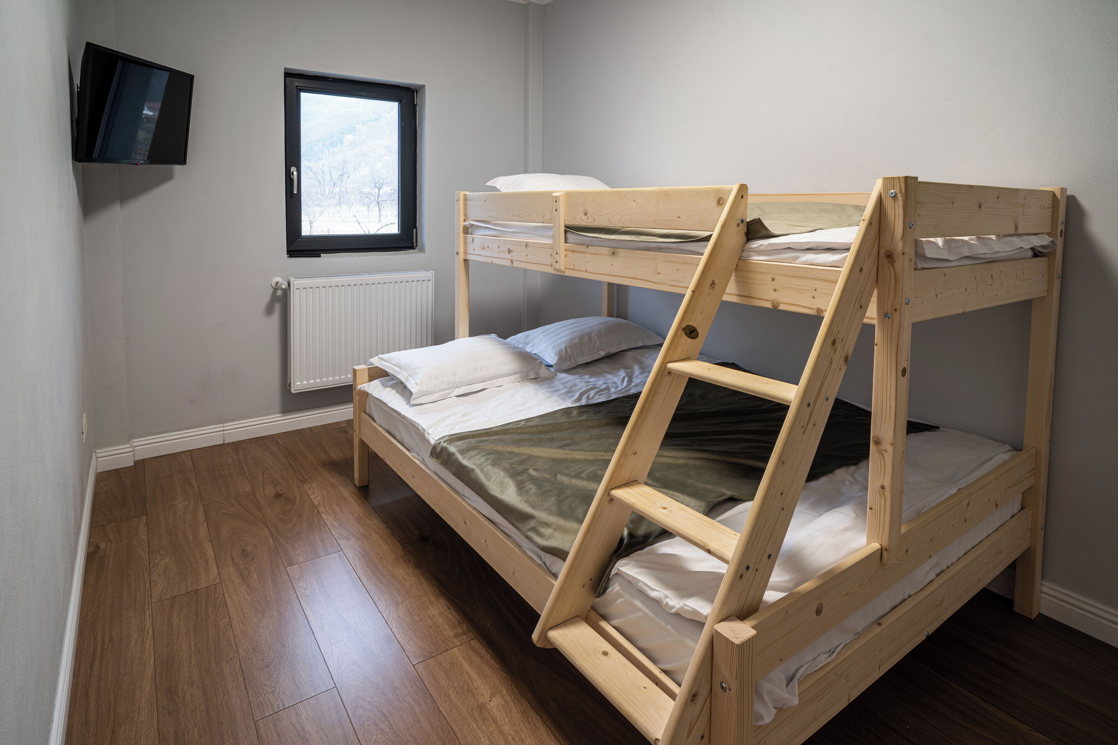 A bunk bed with a wooden frame, a window, and a radiator.