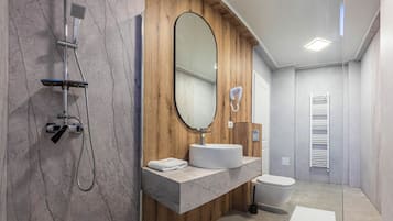 A modern bathroom with a wooden vanity, a large mirror, a built-in sink, a shower, and a toilet.