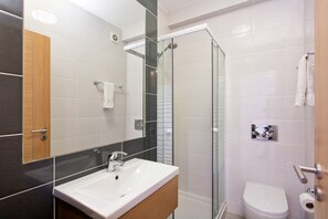 A modern bathroom with a glass-enclosed shower, a white sink, and a toilet.