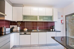 A modern kitchen with white cabinets, a stainless steel sink, and a coffee maker.