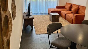 Un salon moderne comprenant un canapé d’angle, une table à manger avec des chaises, une table basse et un téléviseur posé sur un meuble.