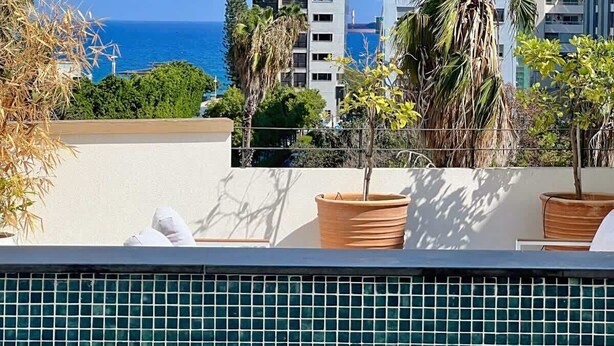 Une piscine sur le toit offrant une vue sur la mer et les bâtiments.