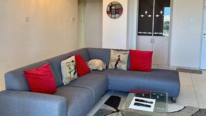 En moderne stue med en grå modulsofa, et sofabord i glas og et tæppe med et mønster.
