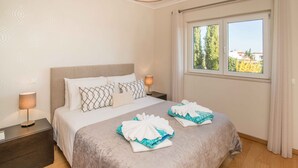 A hotel room with a large bed, two bedside tables, a window with a view, and a ceiling light. - Portimão Elegant House by Homing (Portimão)