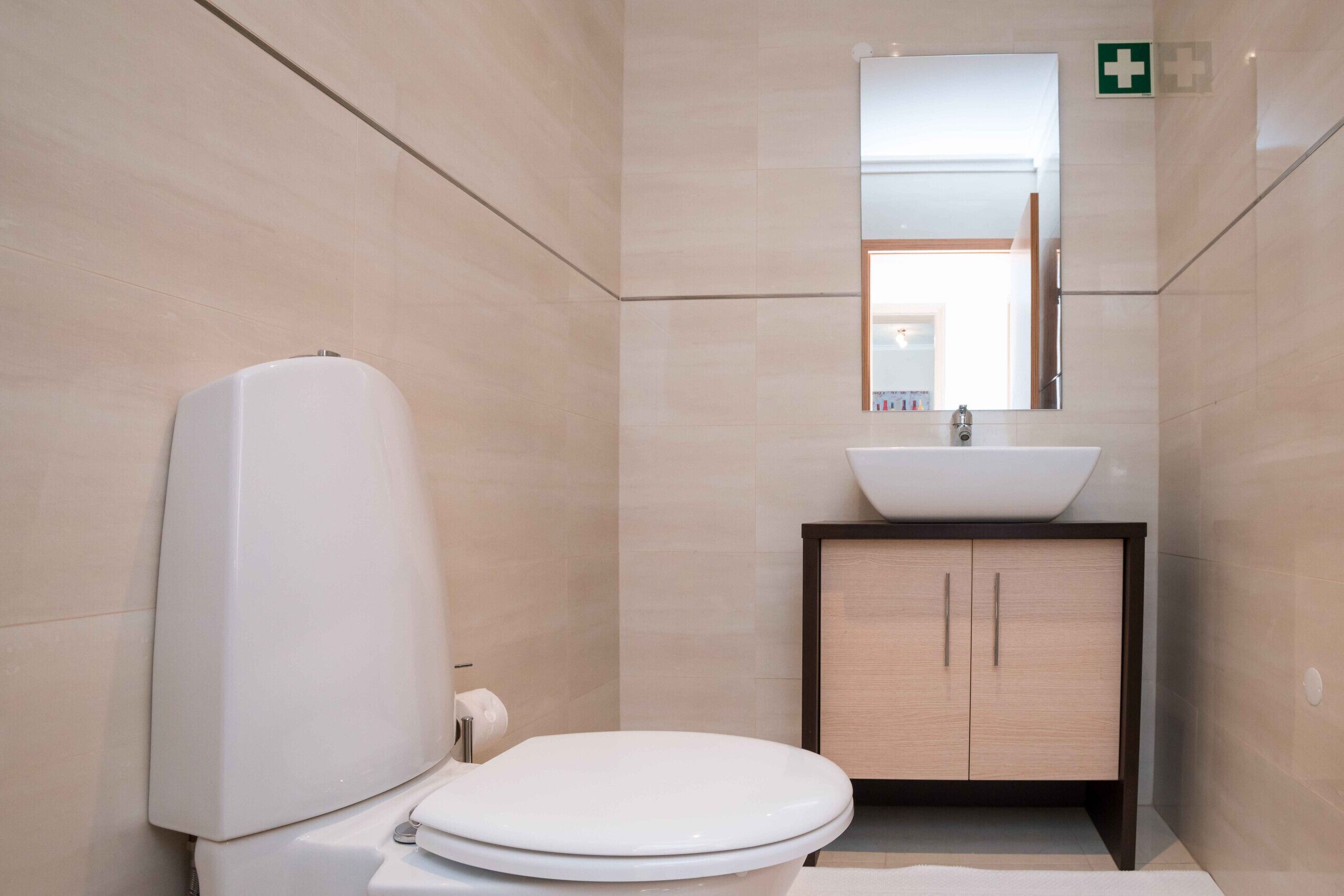 A modern bathroom with a toilet, sink, and cabinet.