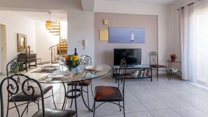 A modern living room with a dining area, a television, and a bookshelf.