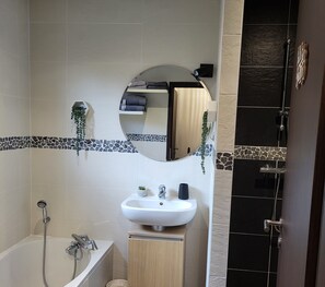 Une salle de bain avec une baignoire, un lavabo, un miroir et une douche.
