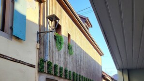 Un bâtiment à la façade en bois, avec une porte de garage et une petite fenêtre ornée de plantes.