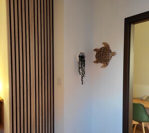Une pièce avec une cloison en lattes de bois, une sculpture de tortue fixée au mur et une plante suspendue.