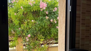 Una cocina con cafetera y ventana que da a un jardín lleno de flores rosas.
