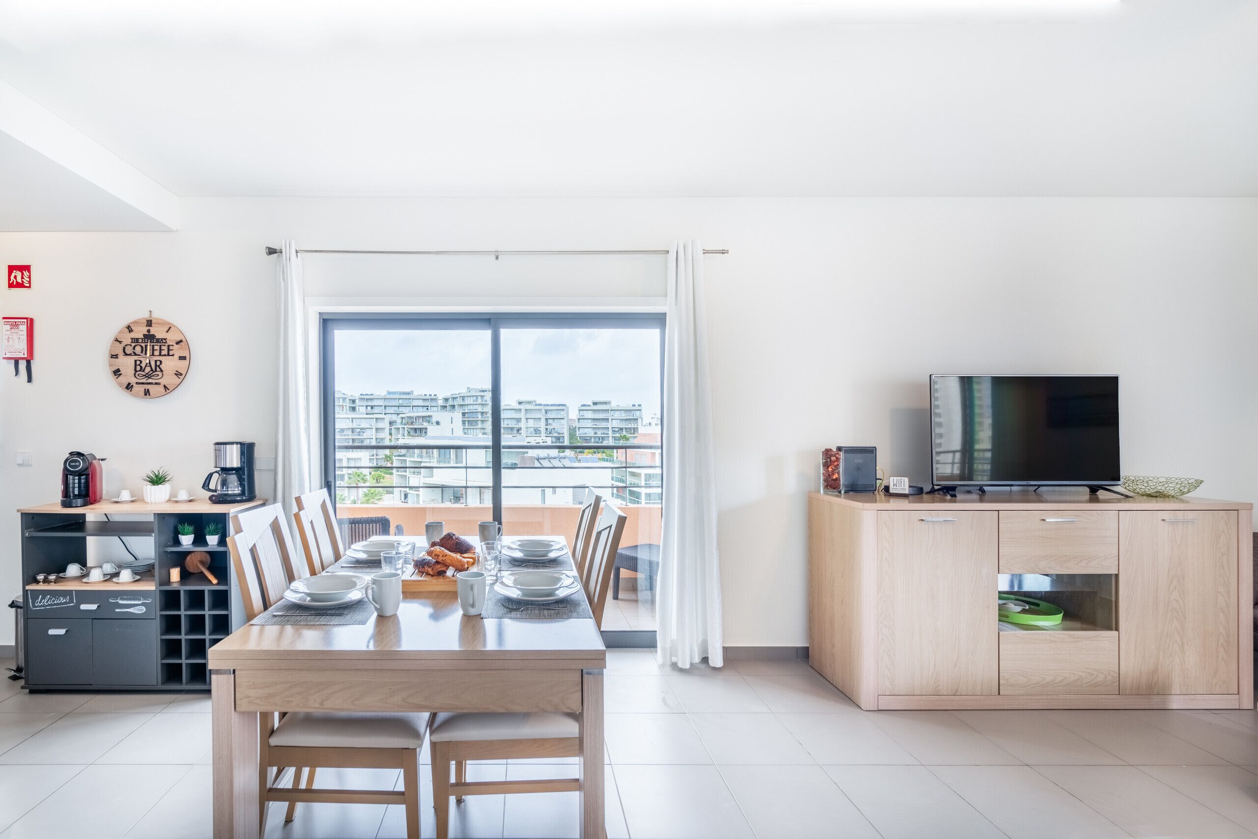 Una sala de estar moderna con comedor, televisor y vistas a la ciudad.