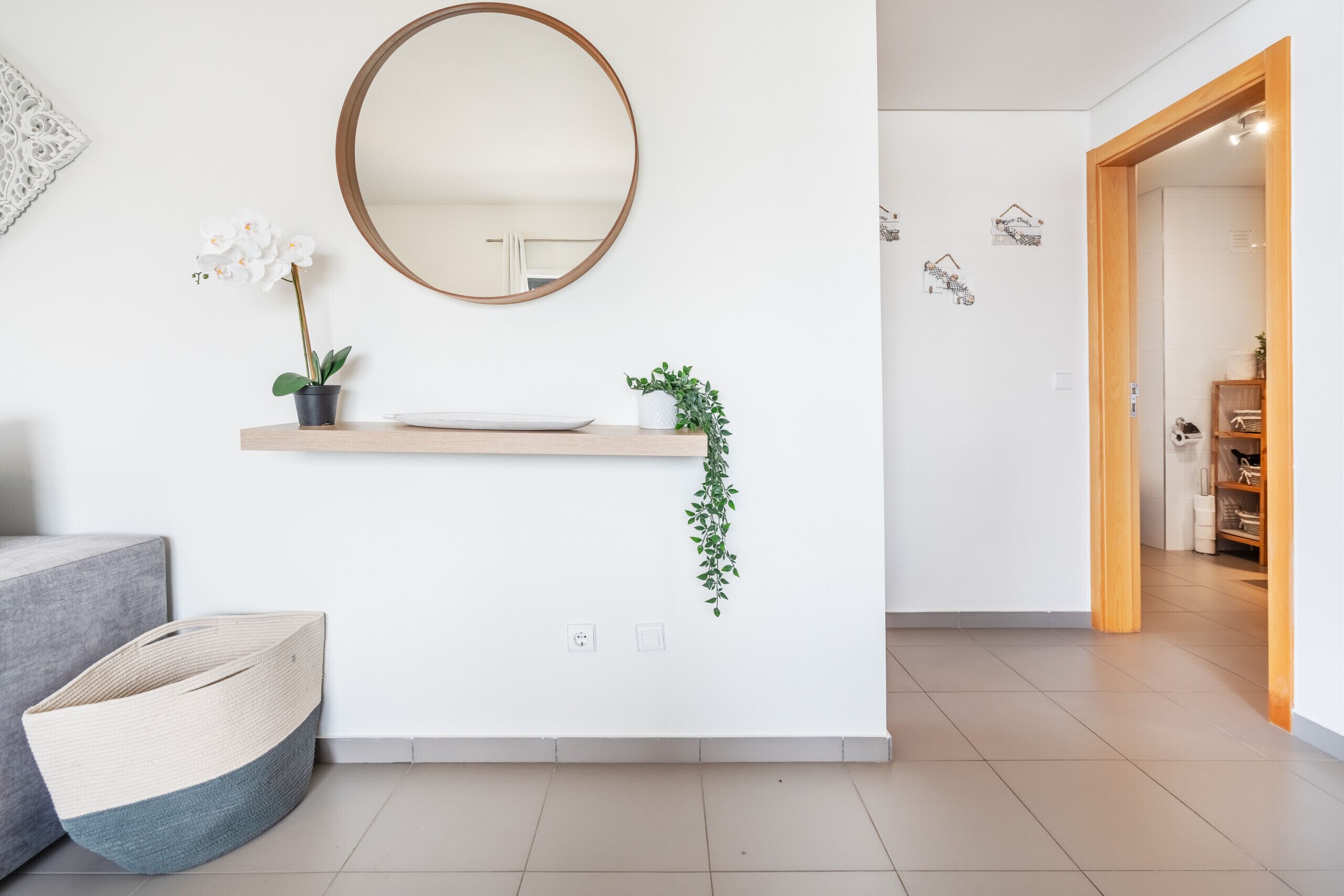 A modern bathroom with a round mirror, a sink, and a potted orchid.