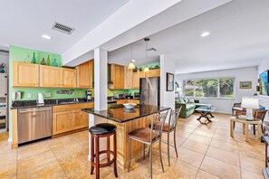 Una cocina amplia con armarios de madera, una isla central con taburetes de bar y un comedor con mesa y sillas.