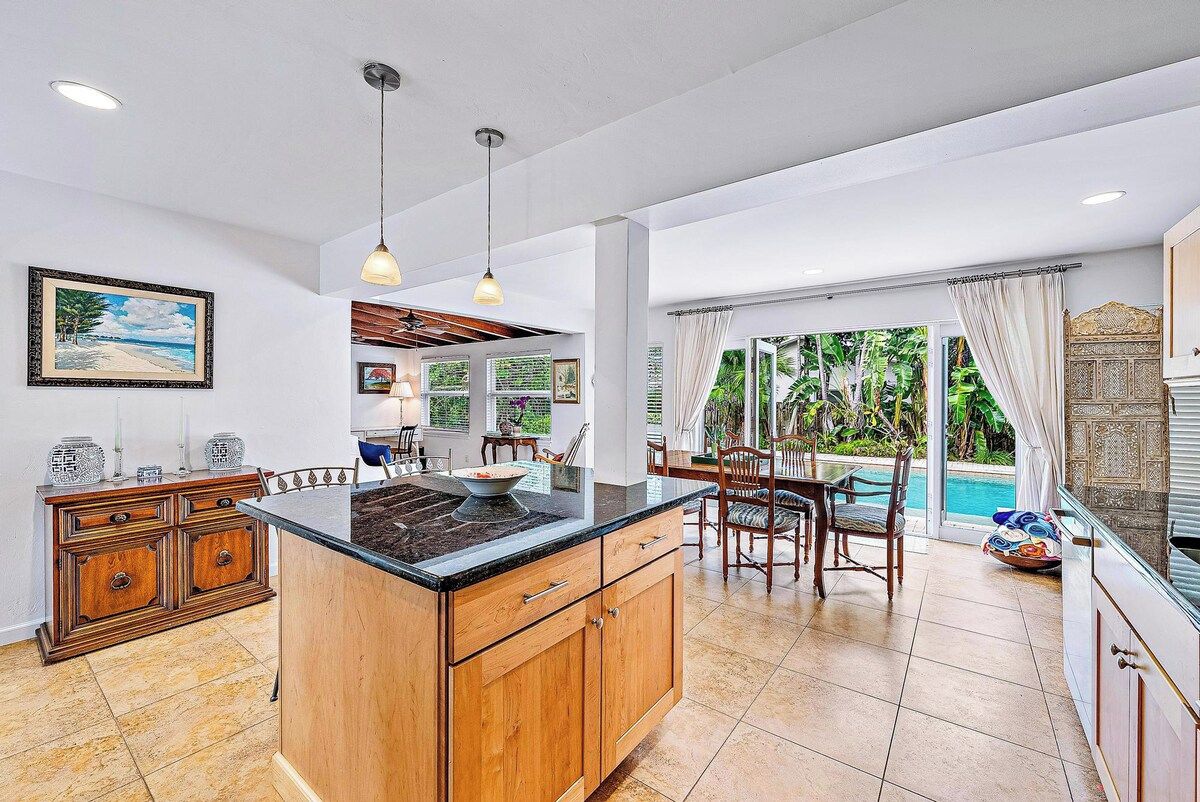 A spacious kitchen with a large island, wooden cabinetry, and a dining area with chairs and a table.