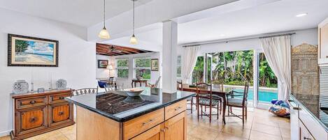 A spacious kitchen with a large island, wooden cabinetry, and a dining area with chairs and a table.