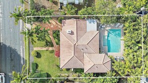 An aerial view of a residential property with a swimming pool, multiple roof sections, and surrounding greenery. - Casa Balsinde - Delight in a Private Pool in the Southern End of West Palm (West Palm Beach)