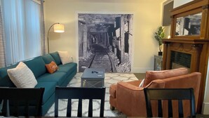 A living room with a sofa, armchairs, a coffee table, and a fireplace. - Executive Mining House Near MTU (Houghton)