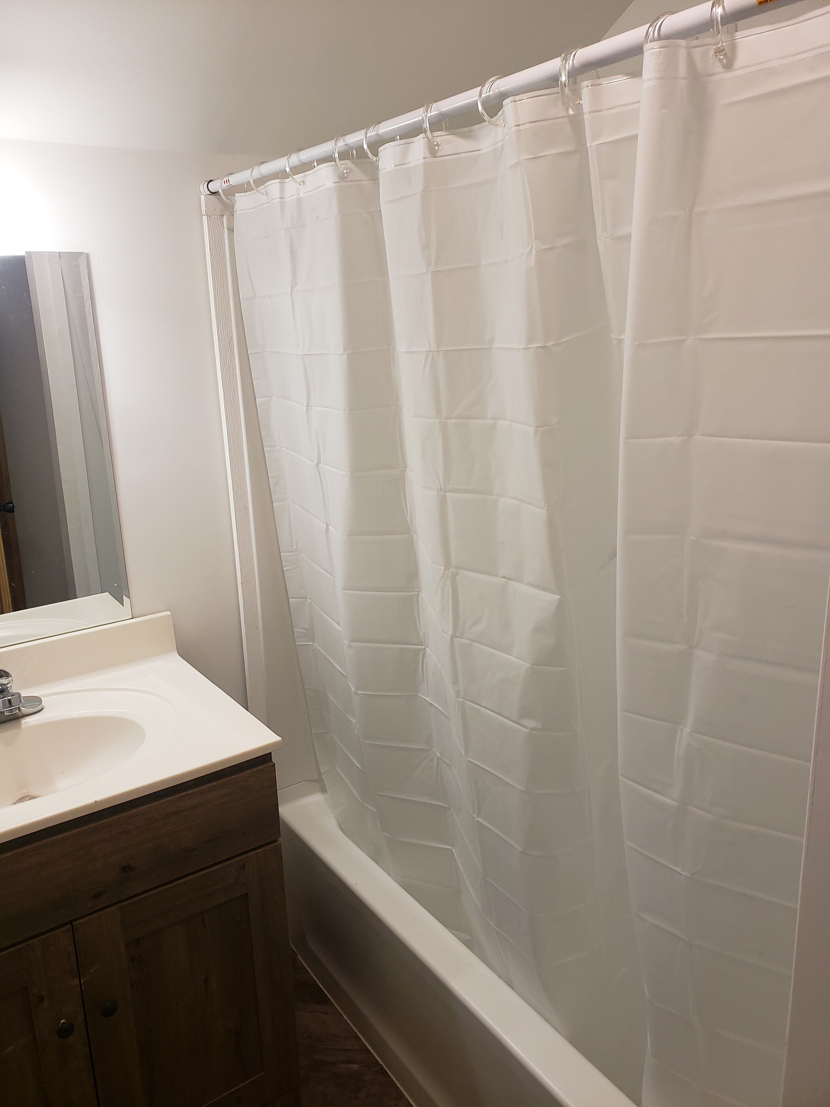 Une salle de bain avec une baignoire blanche, un lavabo blanc et un meuble en bois.