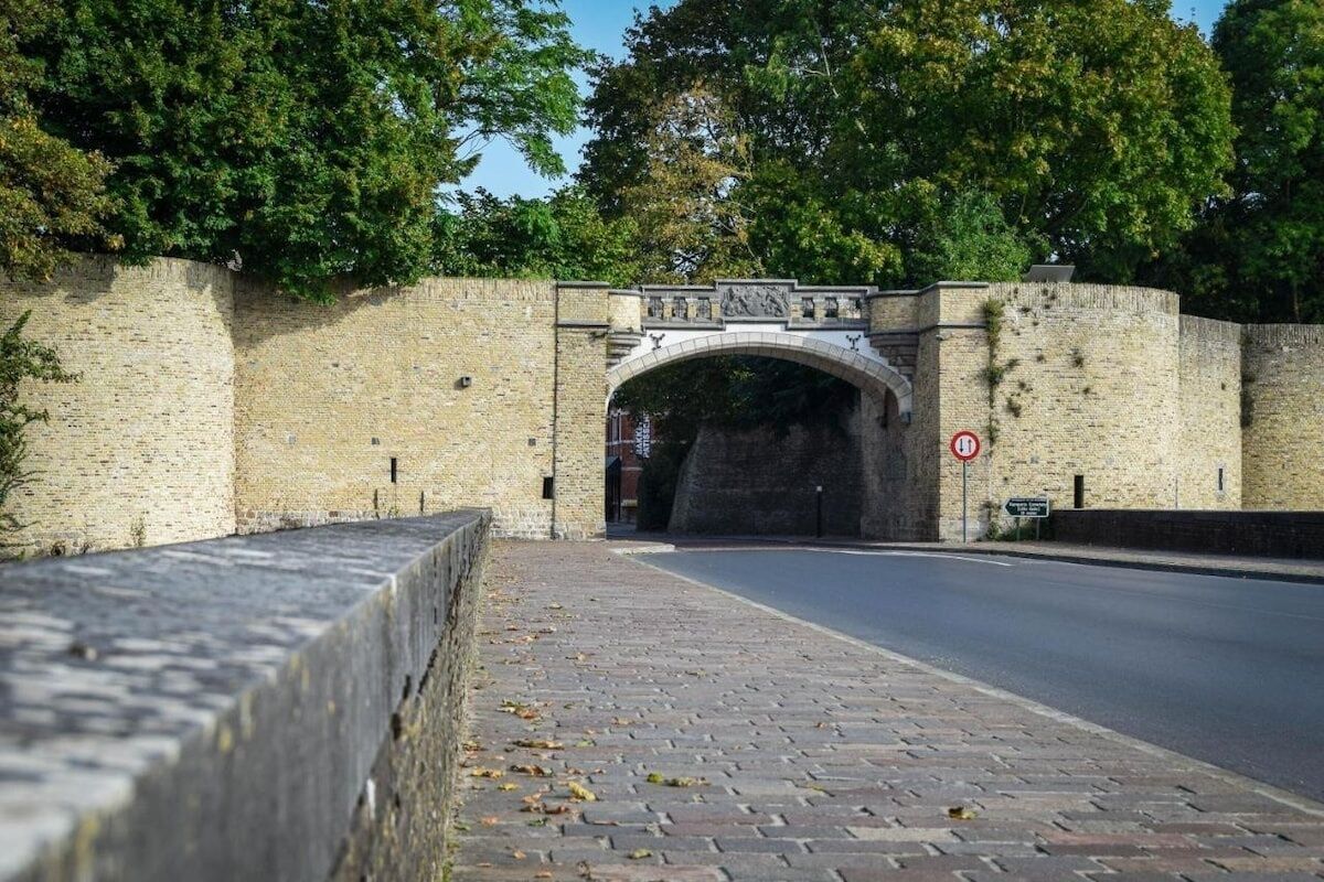 A stone bridge with a sign above it, leading to a tunnel entrance.