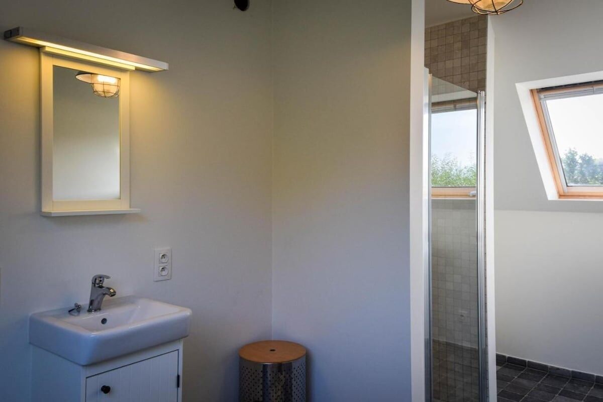 A modern bathroom with a white sink, a mirror, and a shower with a glass door.