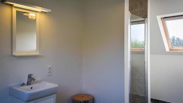 A modern bathroom with a white sink, a mirror, and a shower with a glass door.