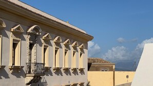 Um edifício com estilo arquitetônico clássico, apresentando uma varanda com grades de metal ornamentadas e uma série de colunas.