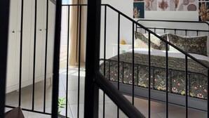 Quarto com cama, escrivaninha e janela.