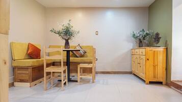 Una habitación acogedora con un sofá amarillo, una mesa de madera con un jarrón y un armario de madera.