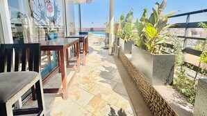 Terraço com mesa, cadeiras, plantas em vasos e vista para a paisagem urbana.
