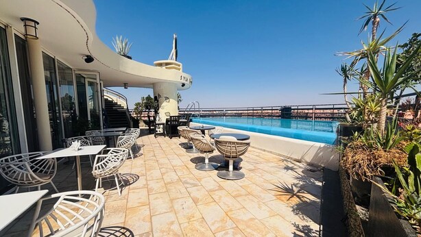 Uma área de piscina no terraço, com assentos ao ar livre e vista clara para o mar.