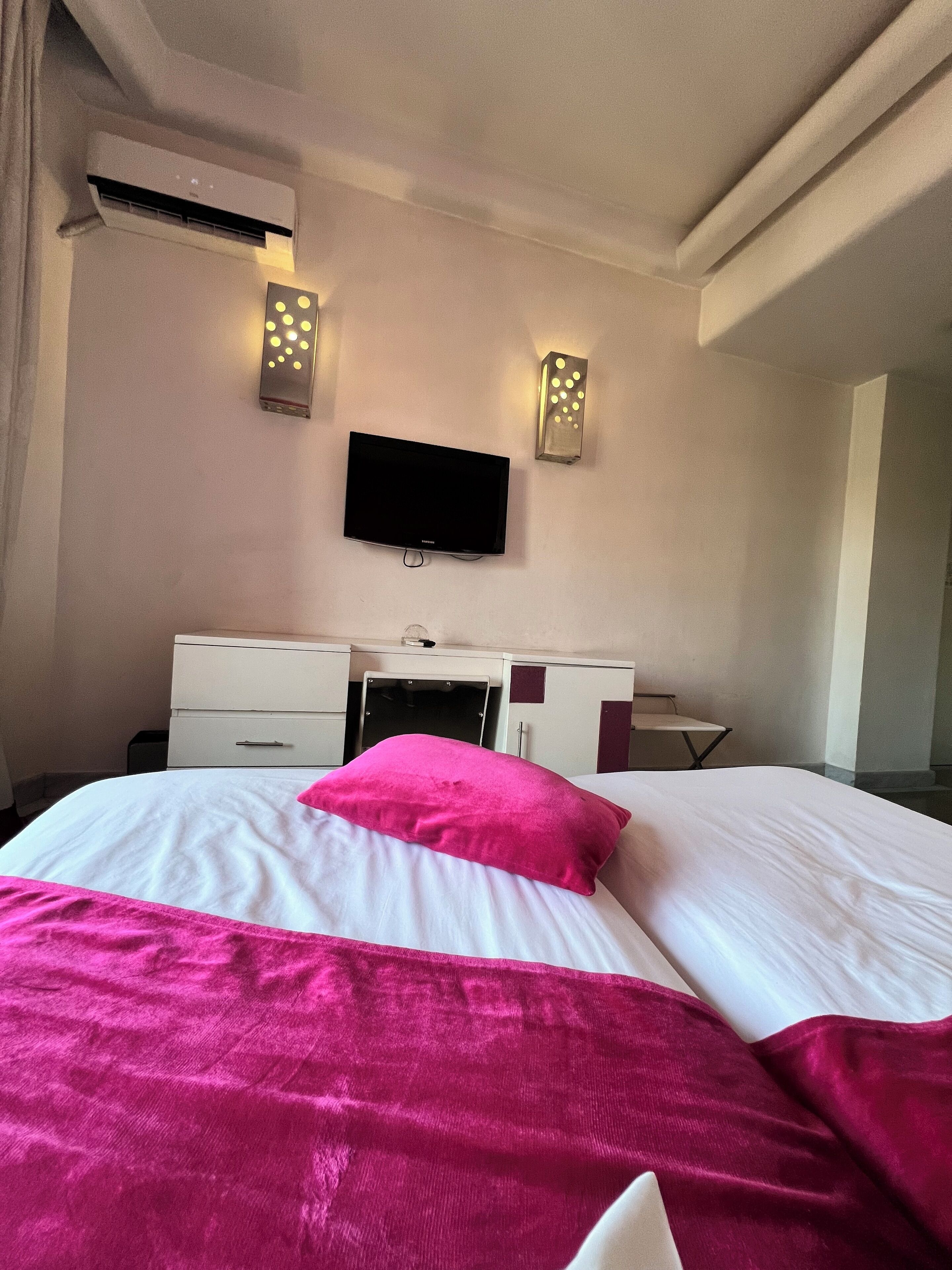 A hotel room with a bed, a TV mounted on the wall, and a wardrobe.