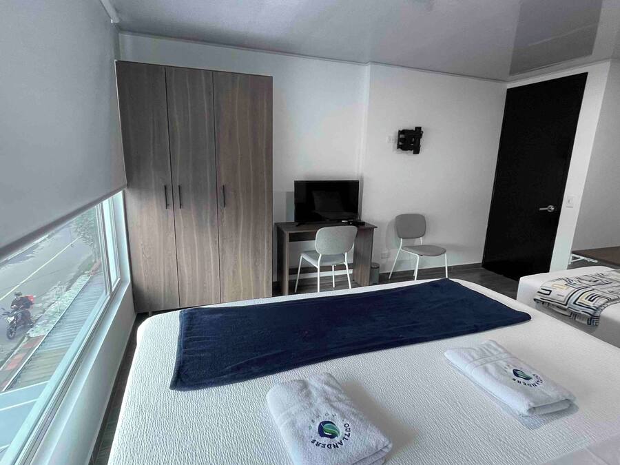 Habitació d'hotel amb llit, escriptori, cadira, televisió i armari.