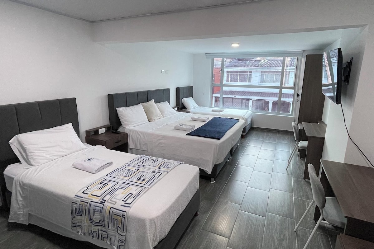 Una habitación de hotel con dos camas, un escritorio y un televisor.