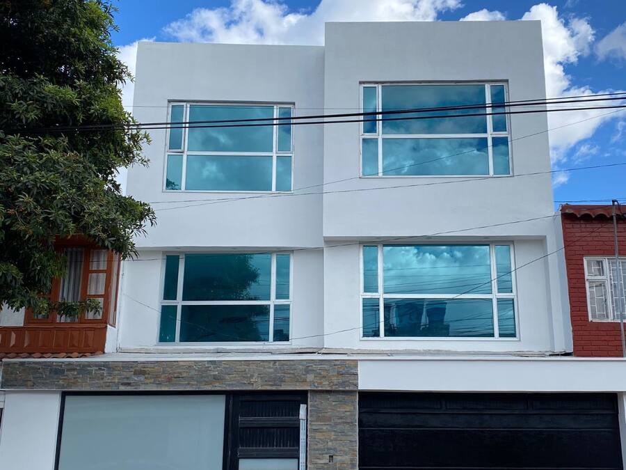 A modern two-story house with a garage, large windows, and a stone facade.