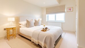 Une chambre à coucher avec un lit, des tables de chevet, une fenêtre et un radiateur.