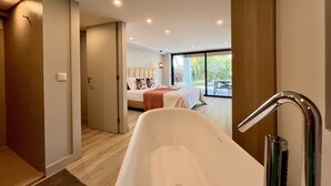 Une salle de bain moderne avec une baignoire sur pieds, un espace douche et une grande fenêtre offrant une vue sur l’extérieur.
