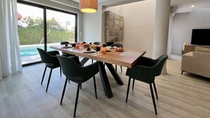 Un espace repas moderne avec une table en bois, des chaises noires et un luminaire suspendu.